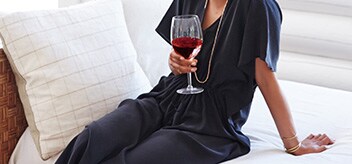 Woman with a glass of white wine sitting on a white couch 
