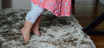 Baby standing on grey carpet
