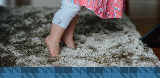 Baby standing on grey carpet
