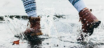 Person with brown boots walking through puddle
