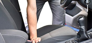 Man leaning into the front seat of a vehicle with grey interior
