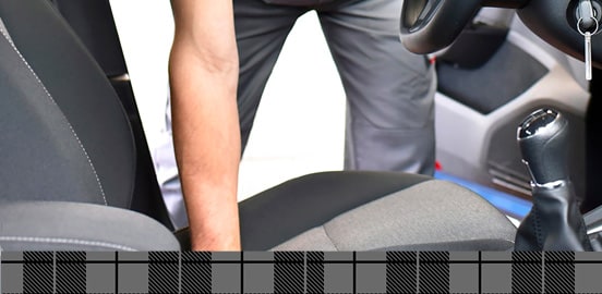 Man leaning into the front seat of a vehicle with grey interior

